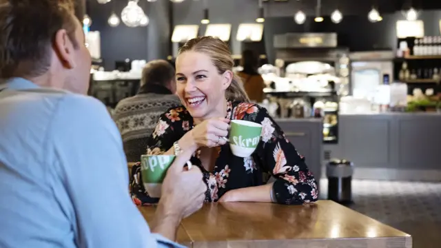 Dame prater med mann over en kopp med kaffe