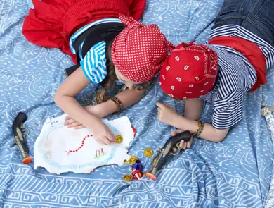 To barn kledd ut som pirater ligger i en seng, sett ovenfra