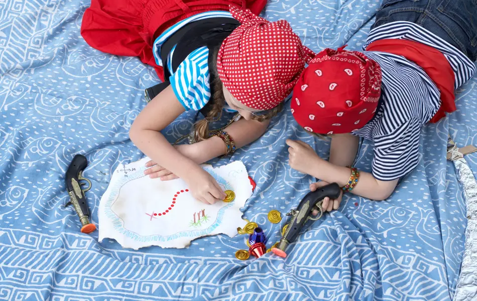 To barn kledd ut som pirater ligger i en seng, sett ovenfra