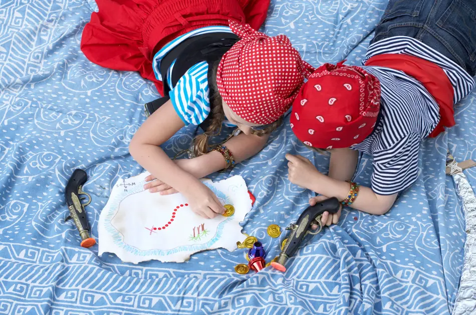To barn kledd ut som pirater ligger i en seng, sett ovenfra
