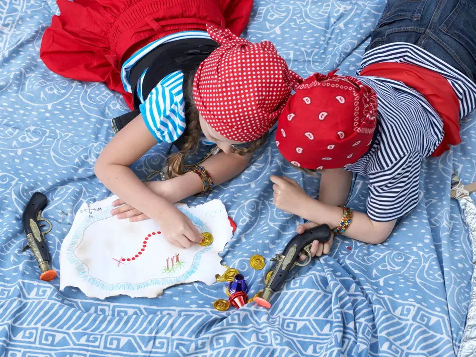 To barn kledd ut som pirater ligger i en seng, sett ovenfra