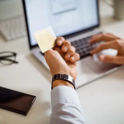 Close up of a man shopping online using laptop with credit card. Man sitting at his desk doing online payment with credit card and laptop.