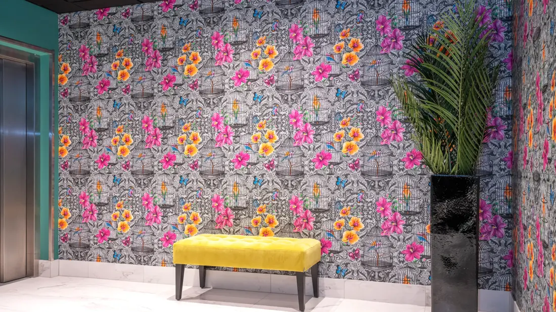 Sorthvit mønstrete tapet med fargerike blomster og sommerfugler og gul puff i reception på Thon Hotel Bristol Bergen