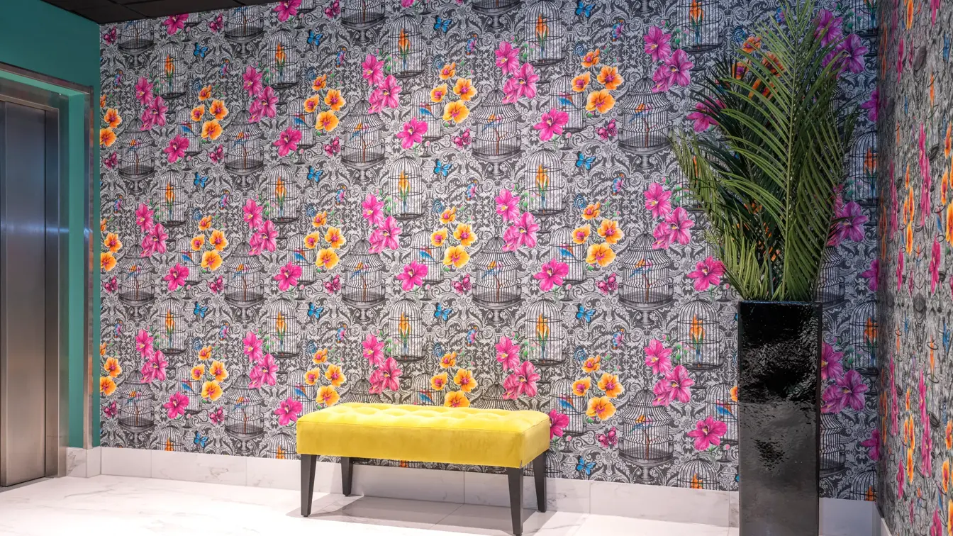 Sorthvit mønstrete tapet med fargerike blomster og sommerfugler og gul puff i reception på Thon Hotel Bristol Bergen