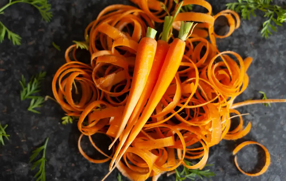 Skrellede gulrøtter på en haug med skall