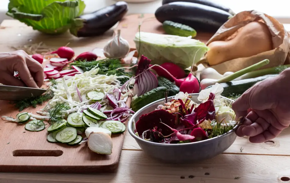 Kvinne hakker grønnsaker på et skjærebrett