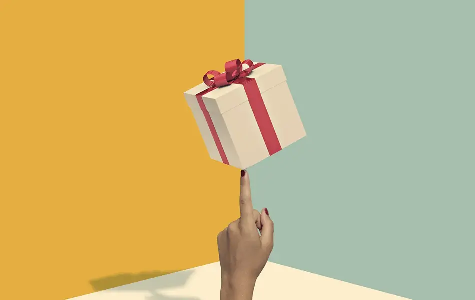 Illustrasjon av firekantet gaveboks med rød sløyfe som balanserer på en finger