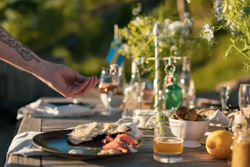 En mann plukker opp et stykke sild fra en tallerken