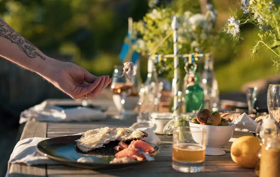 En mann plukker opp et stykke sild fra en tallerken