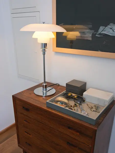 Krom og hvit bordlampe står på en kommode.