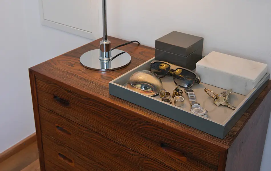 Krom og hvit bordlampe står på en kommode.