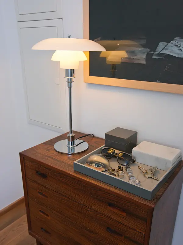 Krom og hvit bordlampe står på en kommode.