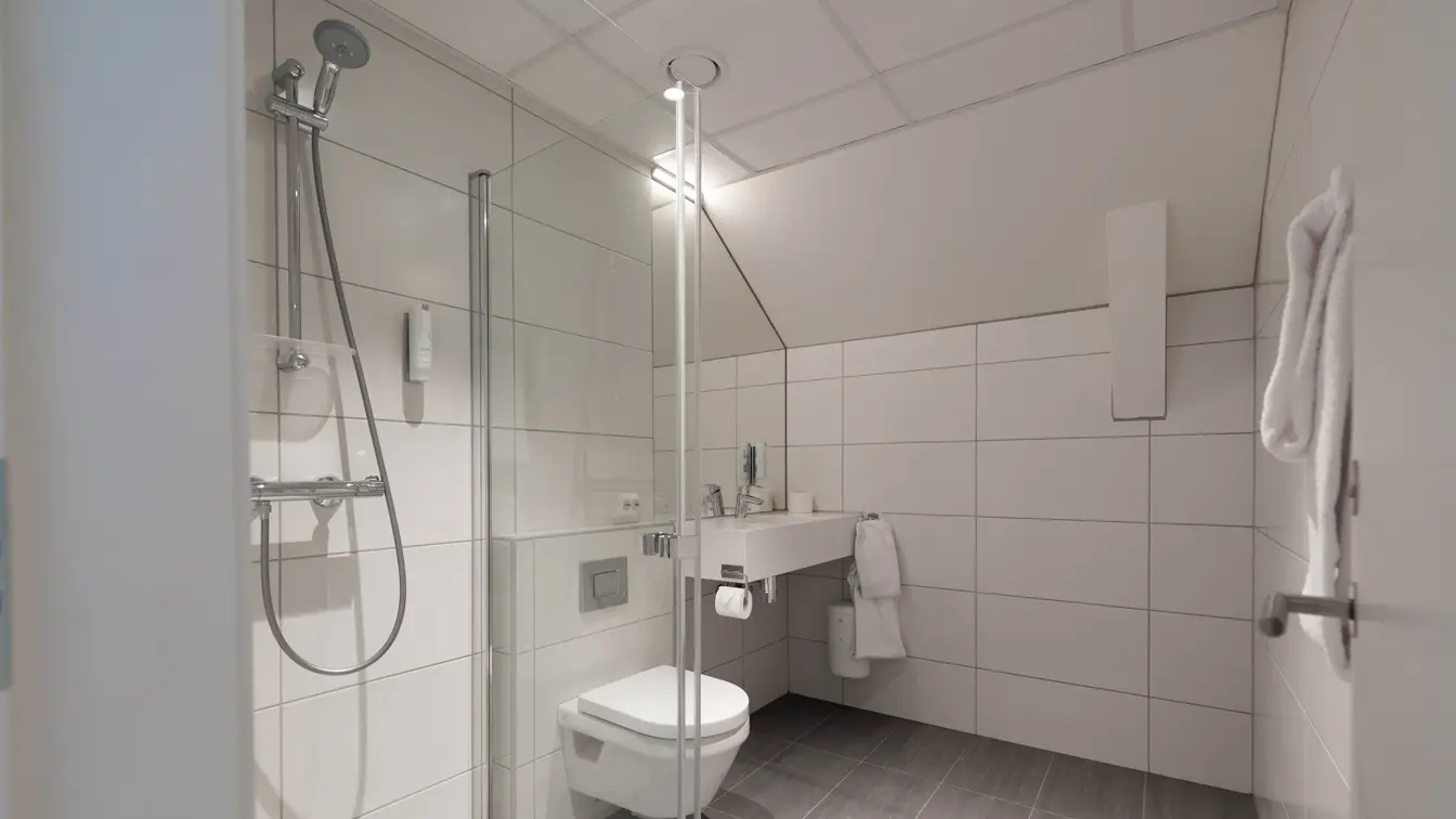 Bilde av hvit bad med dusj, toalett og vask 