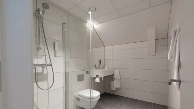 Bilde av hvit bad med dusj, toalett og vask 