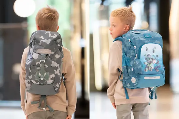 gutt med ryggen til kamera med beige genser og grå spettet skolesekk. Gutt ser til siden og har rygg mot kamera og blå skolsesekk