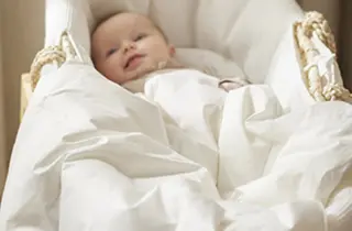 Baby i hvit babynest med sengetøy