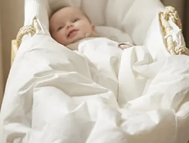 Baby i hvit babynest med sengetøy