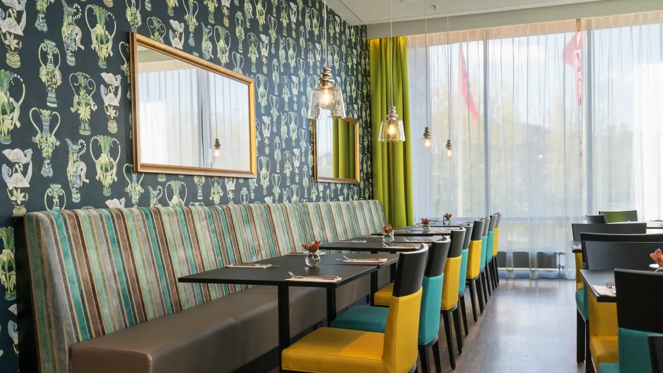 Restaurant Amfi med tapet med karaffler og fargerike stoler og sofabenk på Thon Hotel Arena i Lillestrøm