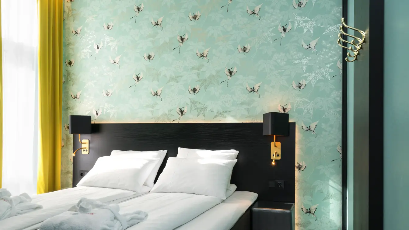 Businessrom med stilfull tapet, dobbeltseng og gule gardiner