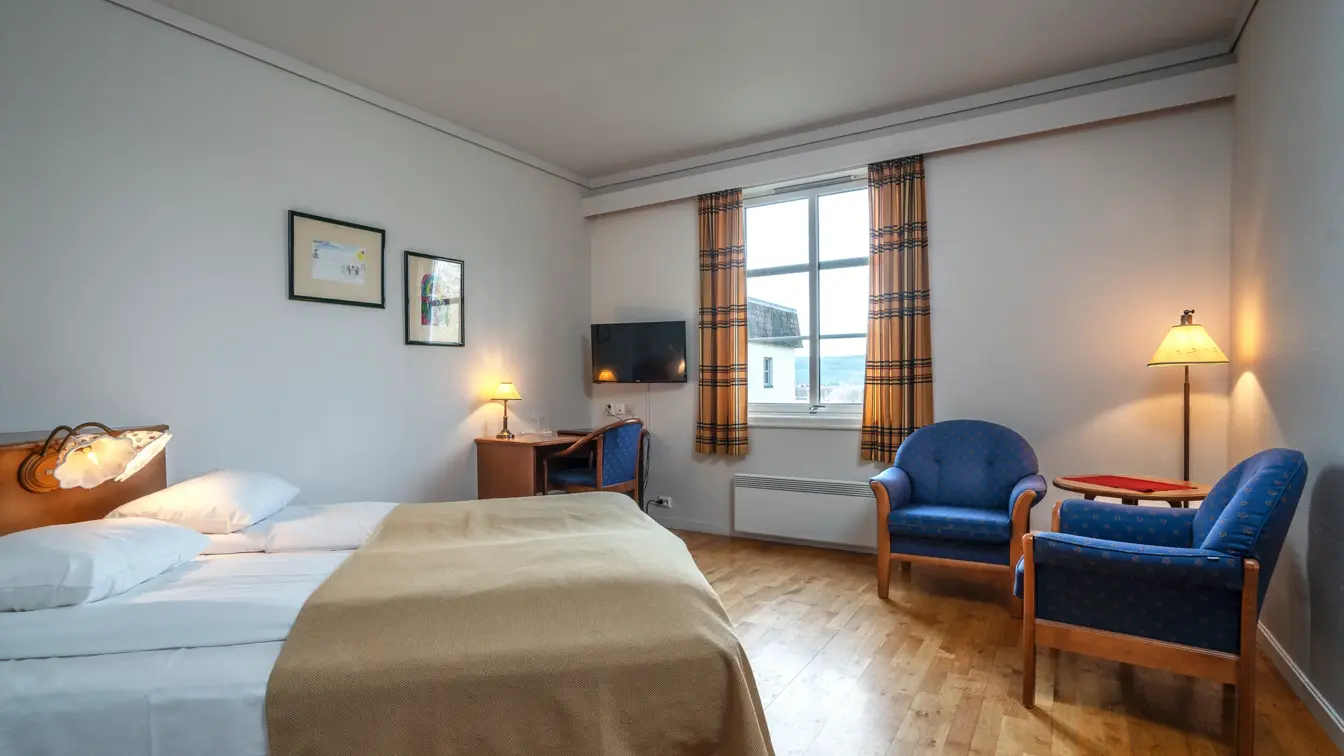 Dobbeltseng, skrivebord og stoler med bord til to personer