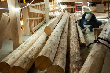 Fagarbeider sitter på huk ved stabler av høvlet tømmer. Foto fra restaureringen innendørs i Kjøpmannsgata 15 i Trondheim.