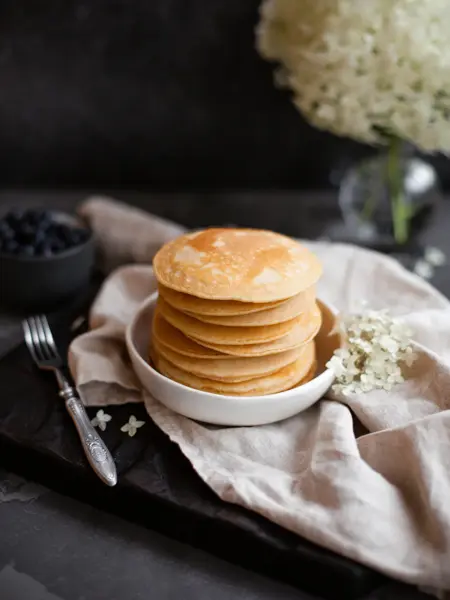 Stack of fresh pancakes decorated with flowers and fresh berries. Healthy breakfast. Copy space.
