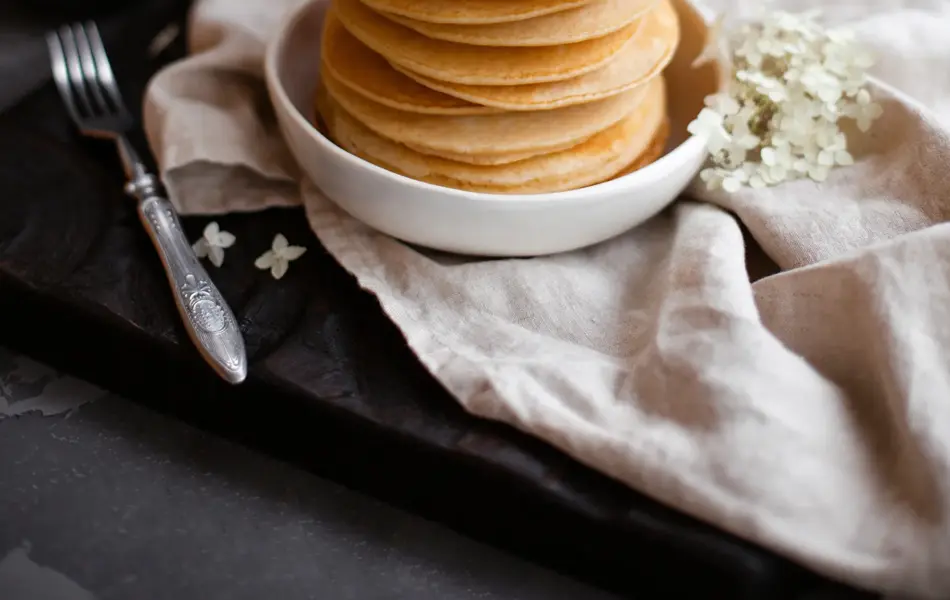 Stack of fresh pancakes decorated with flowers and fresh berries. Healthy breakfast. Copy space.