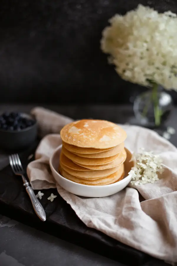 Stack of fresh pancakes decorated with flowers and fresh berries. Healthy breakfast. Copy space.