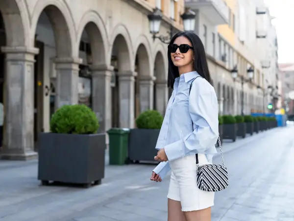 Beautiful young woman standing on street in front of building