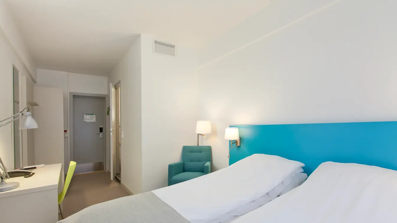 Seng og skrivebord i dobbeltrom på Thon Hotel Munch