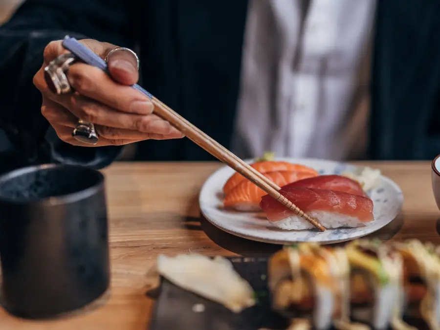 One man, gentleman sitting in restaurant alone, he is eating sushi.