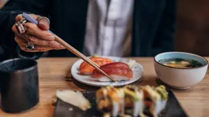 One man, gentleman sitting in restaurant alone, he is eating sushi.