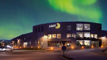 Fasadebilde med nordlys om natten av Amfi Finnsnes