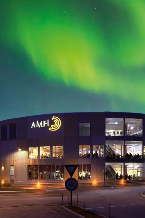 Fasadebilde med nordlys om natten av Amfi Finnsnes