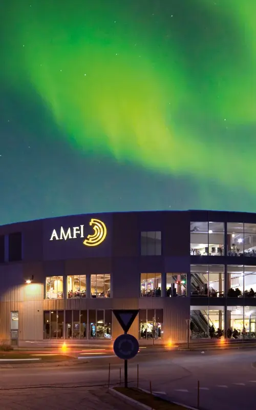 Fasadebilde med nordlys om natten av Amfi Finnsnes