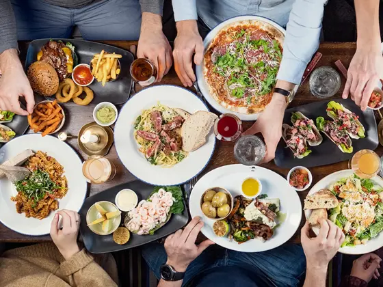 Spisebord med flere personer som spiser med mange tallerkener med ulike retter