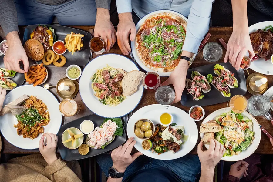 Spisebord med flere personer som spiser med mange tallerkener med ulike retter