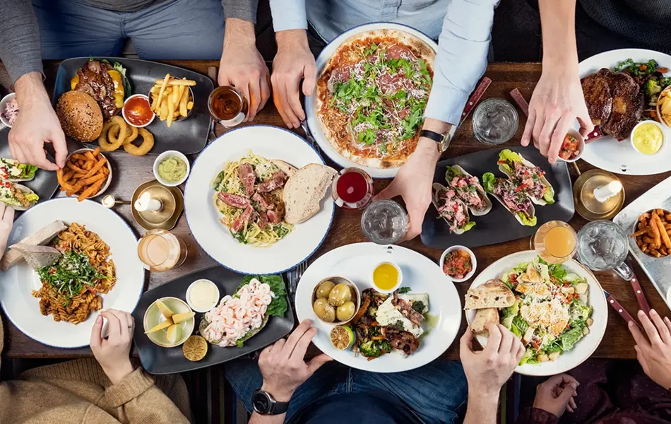 Spisebord med flere personer som spiser med mange tallerkener med ulike retter