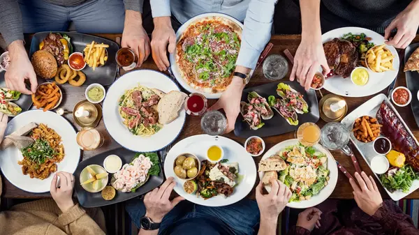 Spisebord med flere personer som spiser med mange tallerkener med ulike retter