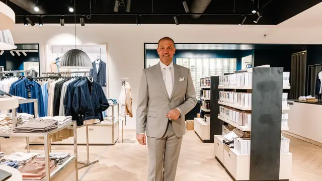 mann i dress står i butikk