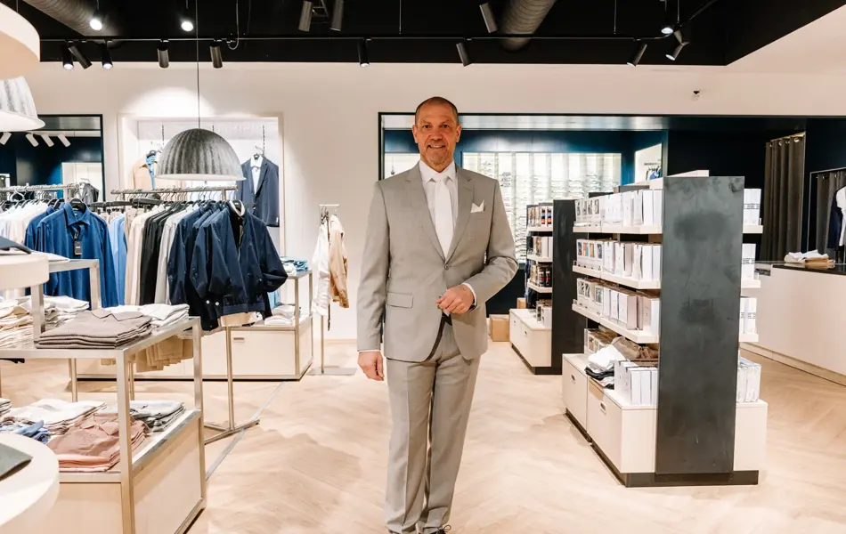 mann i dress står i butikk