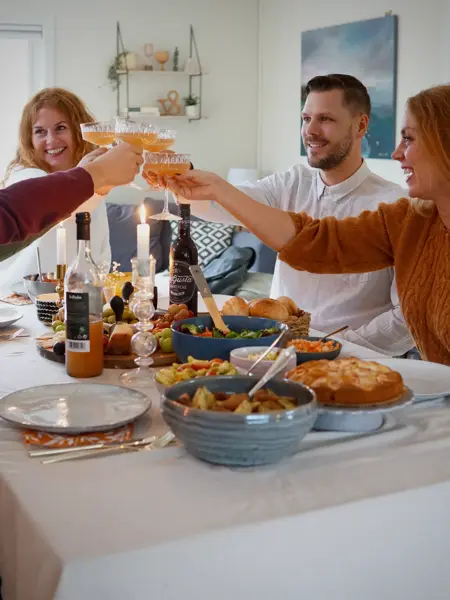 Dekket bord med mat og folk som smiler og skåler
