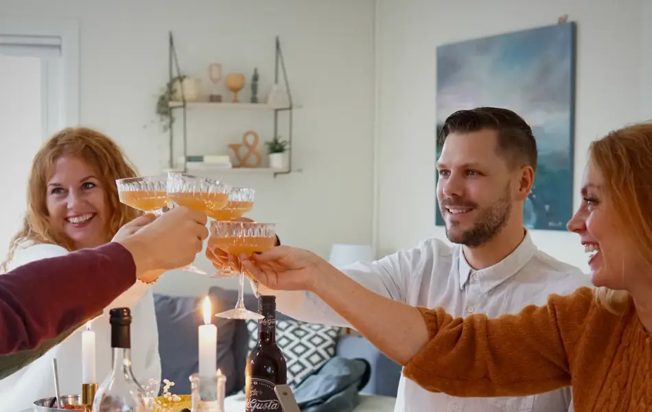 Dekket bord med mat og folk som smiler og skåler