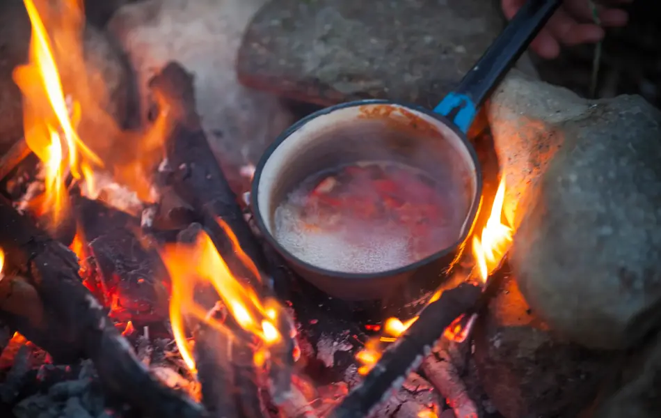 Preparing Food in Cooking Pot on Campfire.