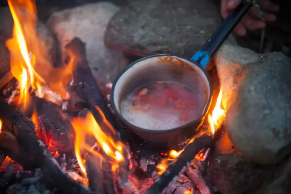 Preparing Food in Cooking Pot on Campfire.