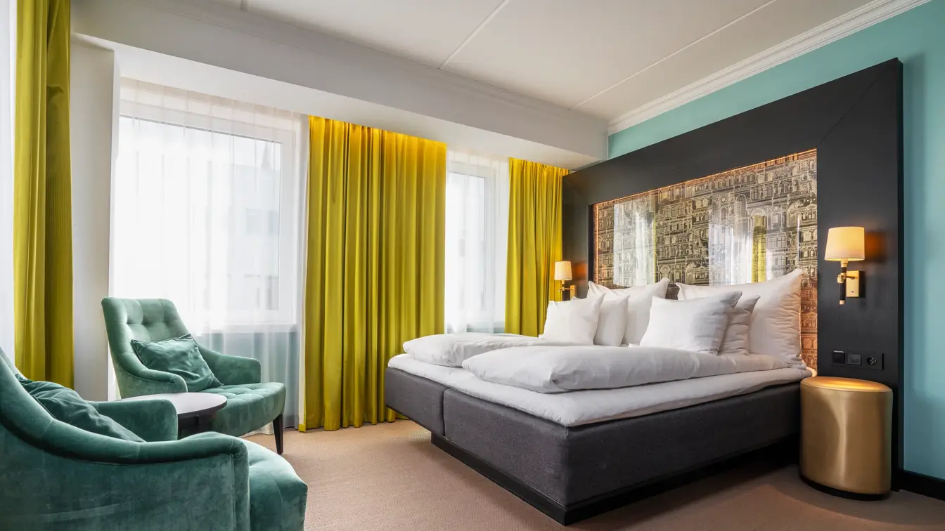 Superior rom med dobbeltseng, grønne velour lenestoler, gule gardiner.
