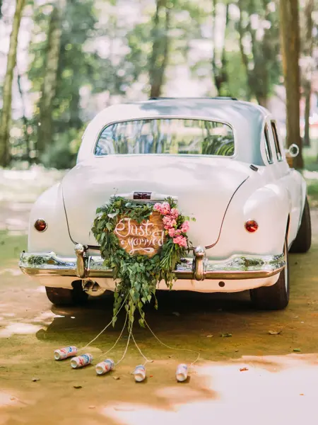 Bumper of retro car with just married sign and cans attached.