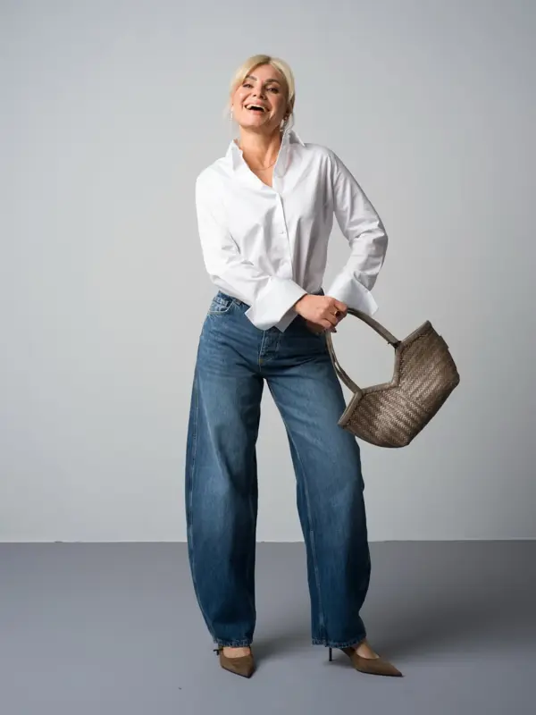 Marianne i hvit skjorte, jeans, pumps og veske