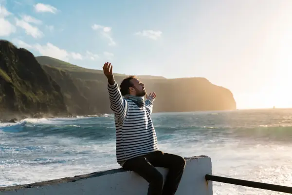 Mann i stripete genser som strekker ut armene.