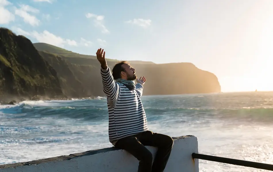 Mann i stripete genser som strekker ut armene.